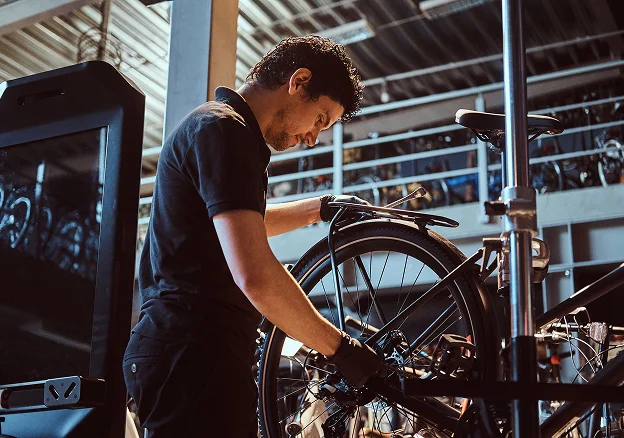 Mécanicien cycliste avec des gants noirs répare une roue de vélo à Montluçon dans l'Allier 03