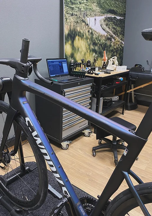 Vélo de route S-Works iridescent monté sur un support d'entraînement, avec un ordinateur portable et des outils à Montluçon dans l'Allier 03